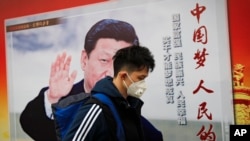 北京街道上，戴口罩的行人走过带有中国领导人习近平像的海报，海报上有标语“中国梦人民的梦”（2017年10月26日）