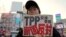 FILE - A protester holds a sign reading "We oppose Japan to join the TPP negotiation talks" during a rally against the Trans-Pacific Partnership in Tokyo. 