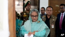 FILE - Sheikh Hasina checks her watch as she waits for the official opening time to cast her vote in Dhaka, Bangladesh, Jan. 7, 2024.