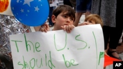 六岁男孩舒阿·里奇跟着母亲参加在凯文·约德众议员在堪萨斯州欧芙兰帕克的办公室外的机会，抗议政府的移民政策。（2018年6月22日）