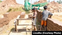 រូបឯកសារ៖ ក្មេងប្រុសពីរនាក់កំពុង​លើ​ដុំ​ឥដ្ឋ​ដាក់​លើ​រទេះ​ឈើមួយ នៅ​សិប្បកម្មឡឥដ្ឋមួយកន្លែងនៅប្រទេស​កម្ពុជា។ (រូបថតដោយ Licadho)