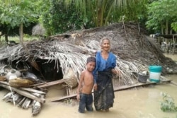 Seorang nenek dan cucunya berdiri depan rumah mereka yang rusak akibat banjir bandang di Desa Haitimuk di Flores Timur pada 4 April 2021. Banjir bandang dan tanah longsor melanda Indonesia bagian timur dan negara tetangga, Timor Leste. (Foto: AFP/Joy )