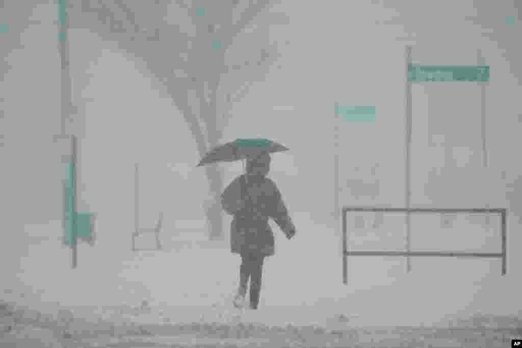 A person holds an umbrella as they walk during a winter storm, Jan. 6, 2025, in Cincinnati, Ohio. 