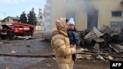 A local resident and her child walks past the railway station destroyed by a Russian missile attack in Kostyantynivka, Donetsk region, on Feb. 25, 2024, amid Russia's invasion of Ukraine.