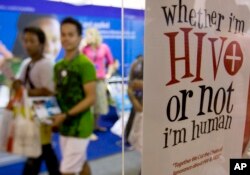 Peserta berjalan melewati poster pada International Congress on Aids ke-9 di Nusa Dua, Bali, Senin, 10 Agustus 2009. (Foto: AP)