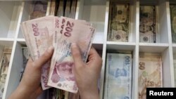 FILE - A money changer counts Turkish lira at an currency exchange office in Istanbul, Aug. 21, 2015. 