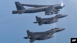 Pesawat B-52H Stratofortress Angkatan Udara A.S., atas, terbang dalam formasi dengan pesawat tempur F-15K Angkatan Udara Korea Selatan di atas laut barat semenanjung Korea selama latihan udara bersama di Korea Selatan, Senin, 6 Maret 2023. (Foto: melalui AP)