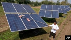 Farmer Pravinbhai Parmar cleans a solar panel installed at a farm in Dhundi village of Kheda district in western Indian Gujarat state, India, Jan. 13, 2023. 
