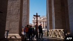 Pilgrims carry a wooden cross at St Peter's square in the Vatican as Pope Francis is still hospitalized with pneumonia on March 06, 2025.