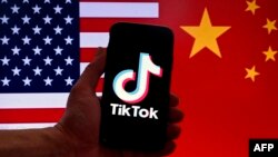 រូបឯកសារ៖ នៅក្នុងរូបថតនេះ រូបសញ្ញាកម្មវិធីប្រព័ន្ធផ្សព្វផ្សាយសង្គមសម្រាប់ TikTok ត្រូវបានបង្ហាញនៅលើអេក្រង់ទូរស័ព្ទ iPhone នៅពីមុខទង់ជាតិសហរដ្ឋអាមេរិក និងទង់ជាតិចិន។
