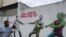 FILE - A man passes graffiti depicting a likeness of Brazilian President Jair Bolsonaro and a coronavirus character engaged in a tug-of-war with health workers, in Sao Paulo, Brazil, June 10, 2020. The text in red reads: "Which side are you on?"