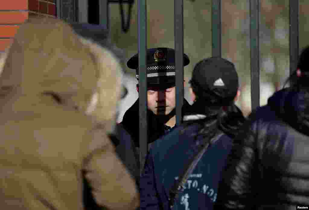 在北京红黄蓝幼儿园门口,门内的保安人员看着门外的人(2017年11月24日)。在该园入托的幼儿家长和社会关注人群连续多日冒着刺骨寒风在幼儿园门外伫立,表达不满。一些不明身份人员在场监视,并用手机拍摄幼儿家长接受采访的过程。