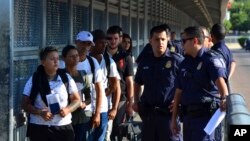 Pejabat Pabean dan Patroli Perbatasan AS menunggu untuk menyerahkan dokumen parpencari suaka kepada pejabat Meksiko, di jembatan internasional antara Laredo, Texas, dan Nuevo Laredo, Meksiko, 10 Juli 2019. (Foto: dok).