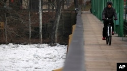 A man bikes over a bridge that spans the partially frozen Delaware River in Trenton, New Jersey, Jan. 16, 2018.