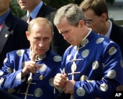 2001年10月21日 ,俄罗斯总统弗拉基米尔·普京和美国总统乔治·布什穿着中国传统丝绸外衣,在亚太经济合作组织(APEC)上海峰会上参加全家福合影时交谈。