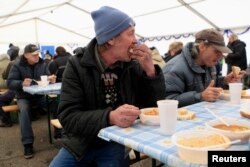FILE - A man eats at a soup kitchen where the Hungarian Ecumenical Charity distributes free lunch to the needy ahead of Christmas in Budapest, Dec. 23, 2013.