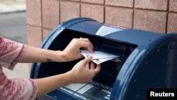 Seoran warga memasukan surat-surat ke kotak surat di Philadelphia, Pennsylvania, Jumat, 14 Agustus 2020. (Foto: Reuters)
