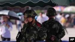FILE - Chinese paramilitary police stand watch at a Beijing railway station, guarding against attacks by Uighur militants, Sept. 3, 2014.