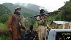 FILE - Pakistani Taliban patrol in their stronghold of Shawal in Pakistani tribal region of South Waziristan, Aug. 5, 2012.