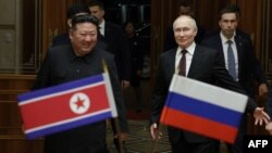 Pemimpin Korea Utara Kim Jong Un (kiri) berjalan bersama Presiden Rusia Vladimir Putin selama upacara penyambutan saat kedatangan Putin di Pyongyang, Rabu 19 Juni 2024.