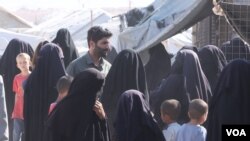 Para perempuan yang ditahan di kamp al-Hol mengerubungi seorang jurnalis sambil mengeluhkan anak-anak mereka yang dibawa ke pusat deradikalisasi, di Suriah, pada 20 Oktober 2021. (Foto: VOA/Ali Zeyno)