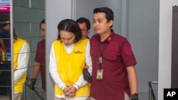 Indonesian Immigration officers escort Yusuke Yamazaki, left, a Japanese fugitive who is wanted for fraud in his home country, prior to his deportation in Batam, Indonesia, March 12, 2024.