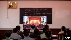 资料照片：广西柳州一个村庄的村民正在观看在北京人大会堂举行的全国脱贫攻坚总结表彰大会的电视直播。（2021年2月25日）