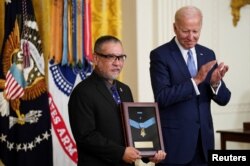 拜登总统在白宫把追赠给美国老兵爱德华·金城的荣誉勋章交予金城的儿子约翰·金城。(2022年7月5日)