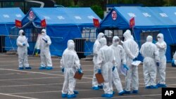 资料照：身穿大白防护服的人负责将来自武汉的人周转到北京某处隔离地点。（2020年4月15日）