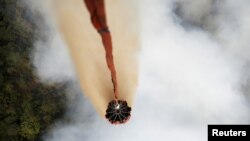 Sebuah pesawat helikopter Mi-17 menyiramkan air di atas hutan yang terbakar di wilayah Ogan Komering Ulu, Sumatra Selatan, 10 September 2015 (Foto: dok). Australia akan mengirim pesawat pemadam kebakaran raksasa dan para penasihat terlatih untuk membantu Indonesia mengatasi kebakaran hutan yang membuat beberapa bagian Asia Tenggara tertutup kabut asap tebal. 