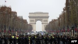 2018年12月15日，在法国巴黎的香榭丽舍大街，防暴警察站在身穿黄色马甲的抗议者面前，这些抗议者抗议高税收导致的生活成本上涨。（法新社）