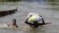 FILE - People wade through a flood with their belongings after their houses were submerged in the Amassoma community in Bayelsa state, Nigeria, Oct. 6, 2012.