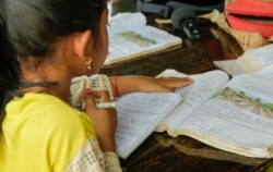 A second-grader follows along as she attends an outdoor classroom at her teacher's house in Samlout district, Battambang province, Cambodia, June 17, 2020. (Hean Socheata/VOA Khmer)