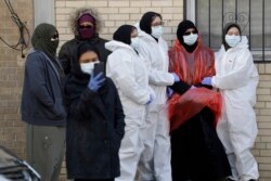 Para pelayat mengenakan pakaian pelindung berkumpul sebelum pemakaman seorang pasien Covid-19, di New York, 22 April 2020.