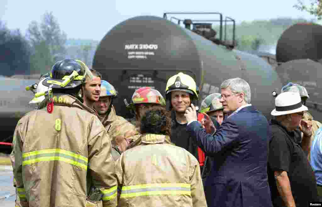 Canada's Prime Minister Stephen Harper speaks with firefighters while he tours the wreckage of the train explosion in Lac Megantic, Quebec, Canada, July 7, 2013.