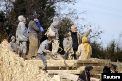 Internally displaced people covered in mud wait at the town of Khirbet Al-Joz to get permission to cross into Turkey, near the Syrian-Turkish border in Syria, Feb. 7, 2016.