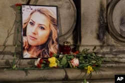 A portrait of slain television reporter Viktoria Marinova is placed on the Liberty Monument next to flowers and candles during a vigil in Ruse, Bulgaria, Oct. 9, 2018.