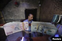 FILE - Banknotes of U.S. dollars and Turkish lira are seen in a currency exchange shop in the city of Azaz, Syria, Aug.18, 2018.