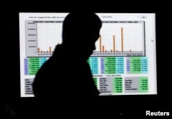 Seorang pria melewati layar perhitungan suara pemilu di kantor Komisi Pemilihan Umum (KPU) Pusat di Jakarta. (Foto: Reuters).