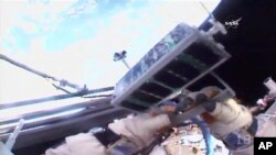 In this image made from video provided by NASA, Russian cosmonaut Sergey Ryazanskiy holds a small satellite before launching it by hand from the International Space Station, Aug. 17, 2017. 