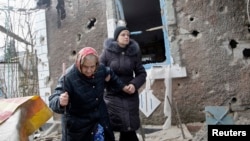 Cư dân đi bộ bên ngoài một ngôi nhà bị hư hại bởi pháo kích ở Donetsk, miền đông Ukraine, ngày 3/2/2015.