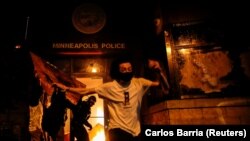 Para pengunjuk rasa ketika membakar pintu masuk kantor polisi di Minneapolis, Minnesota. (Foto: Reuters/Carlos Barria)