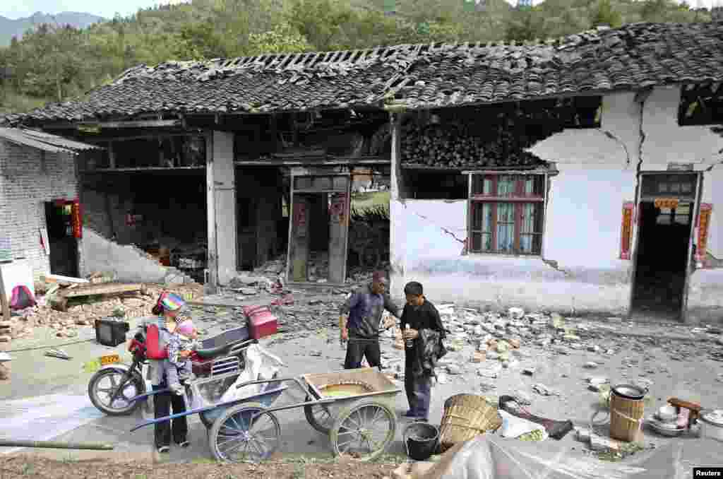 2013年4月20日星期六,中国四川省雅安市芦山县发生里氏7级强烈地震。在龙门乡人们站在被震毁的房屋外面。