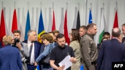 2024年6月16日，乌克兰总统弗拉基米尔·泽连斯基（中）在卢塞恩附近的卢塞恩附近的布尔根施托克胜地出席乌克兰和平峰会全体会议时查看文件。