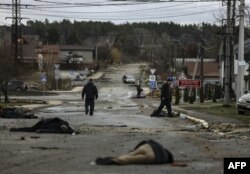 На світлині, зробленій 2 квітня 2022 року, тіла мирних жителів лежать на вулиці Яблунській у Бучі, після того, як російська армія відступила з міста. (Photo by RONALDO SCHEMIDT / AFP)