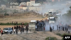 FILE - Palestinians rush trucks as they transport humanitarian aid from the U.S.-built Trident Pier near Nuseirat in the central Gaza Strip on May 18, 2024. The U.N. and other aid agencies say the entry of food and other supplies has plunged dramatically in the past two weeks.