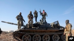Sirijski opozicioni borci stoje na vrhu zaplenjenog vojnog oklopnog vozila na periferiji Hame, Sirija, 3. decembar, 2024. (Foto: AP/Ghaith Alsayed)
