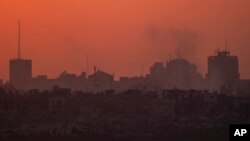 Destroyed buildings stand in the Gaza Strip as the sun sets, as seen from southern Israel on July 17, 2024.