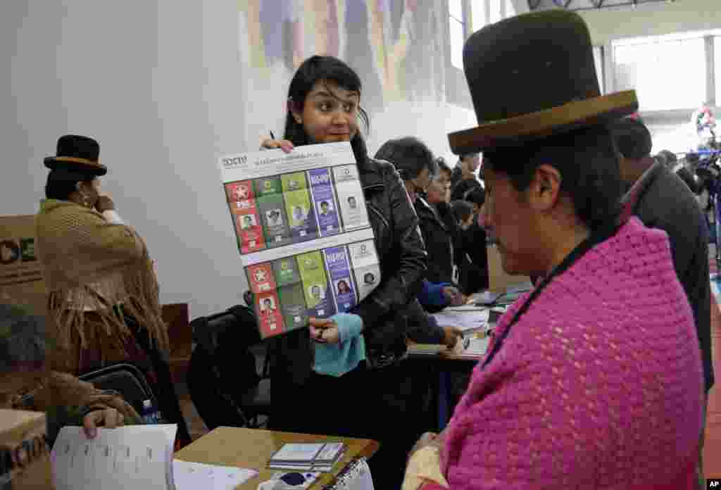 An elections delegate shows an unmarked ballot before giving it to a voter at the polling station in La Paz, Oct. 12, 2014.