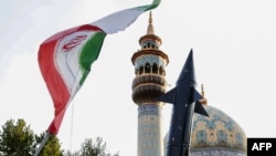 Iranians lift up a flag and the mock-up of a missile during a celebration following Iran's missiles and drones attack on Israel, on April 15 2024, at Palestine square in central Tehran.